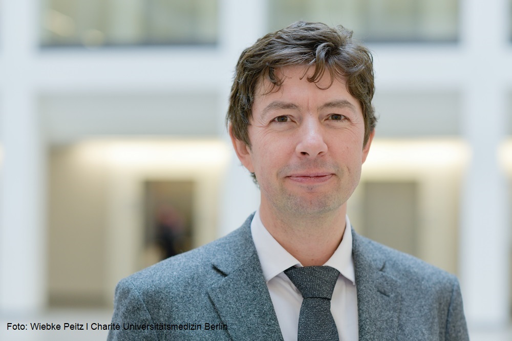 Porträtfoto von Prof. Dr. Christian Drosten, Direktor des Fachbereichs Virologie bei Labor Berlin vor weichgezeichnetem Hintergrund innerhalb eines Gebäudes.